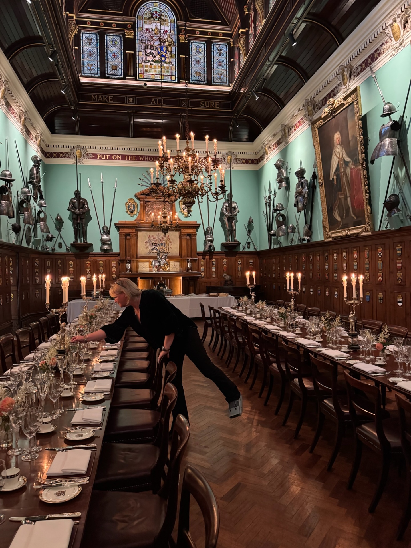 Candlelit grand hall dinner with stained glass windows, suits of armour and long dining tables